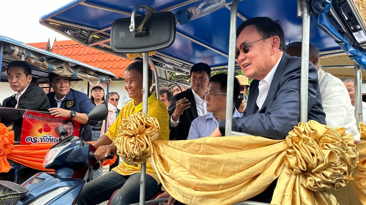 “ทักษิณ” นั่งรถพ่วงข้างเทรูปหล่อหลวงพ่อคูณ เสื้อแดงรอรับแห่ร้องเพลงอวยพรวันเกิดล่วงหน้า